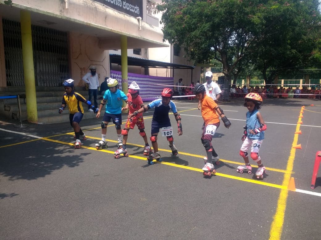 Young children of the school in helmets and skates on the school court